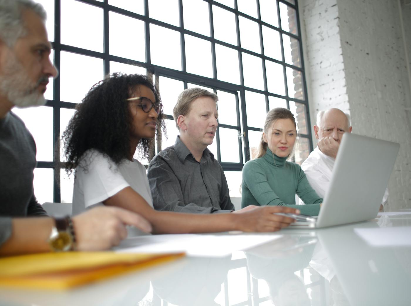 Corporate team collaborating around a laptop in a modern office